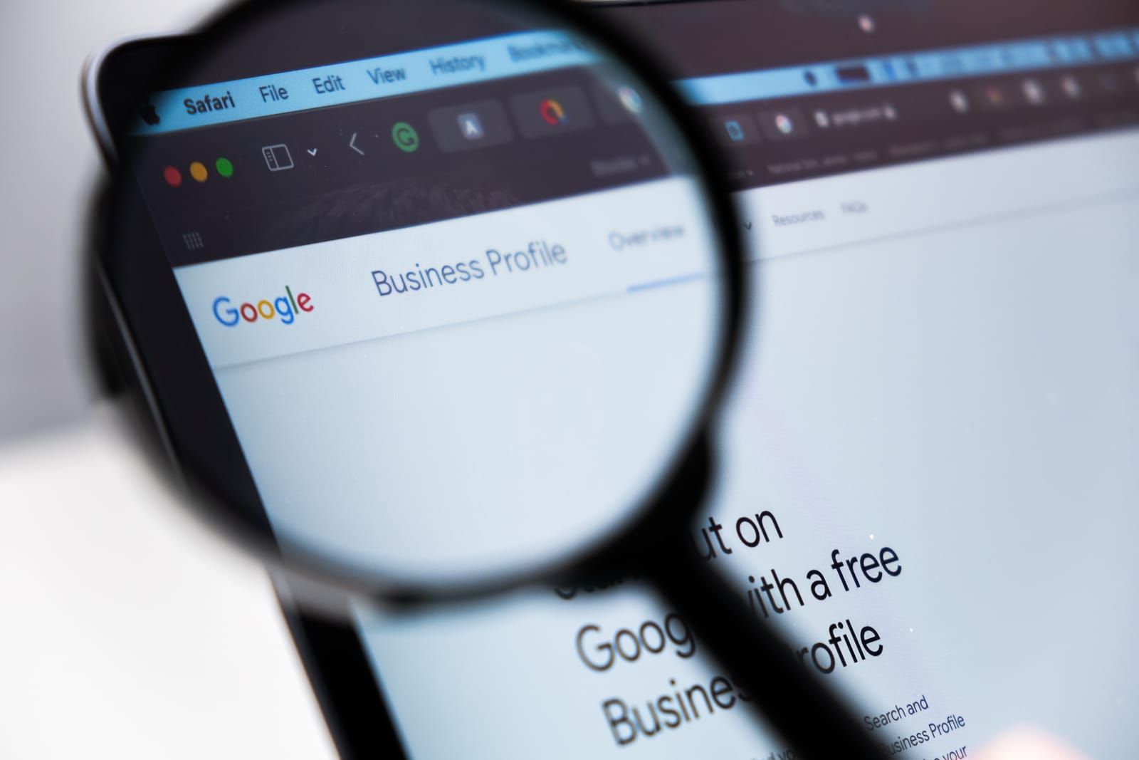 A magnifying glass is looking at a google business profile on a tablet.