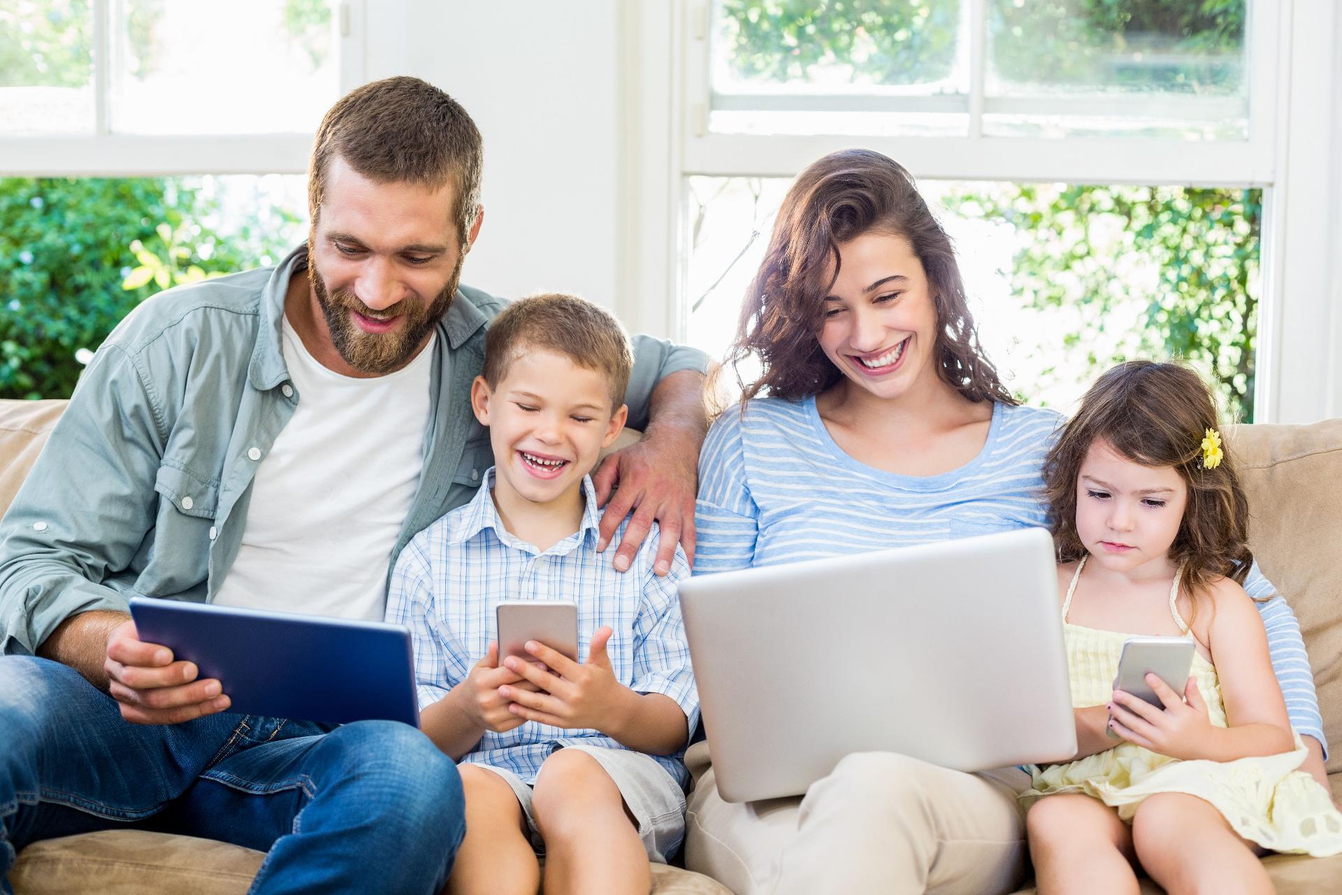 A family on a sofa using an array of digital devices.