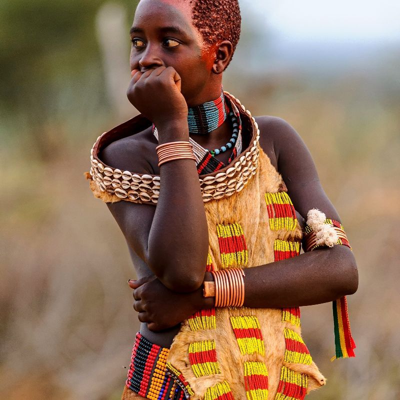 Witness the captivating traditions of the Omo Valley with this powerful portrait of two Mursi men from Ethiopia. They look directly into the camera, showcasing their striking traditional attire, makeup, and hairstyles. The large lip plates worn by the men make for a truly unique and memorable cultural sight. Inspiration Africa specializes in designing your bespoke, tailor-made trip to Ethiopia for respectful cultural immersion and exploring other incredible African destinations. Experience the fascinating Mursi culture with us!