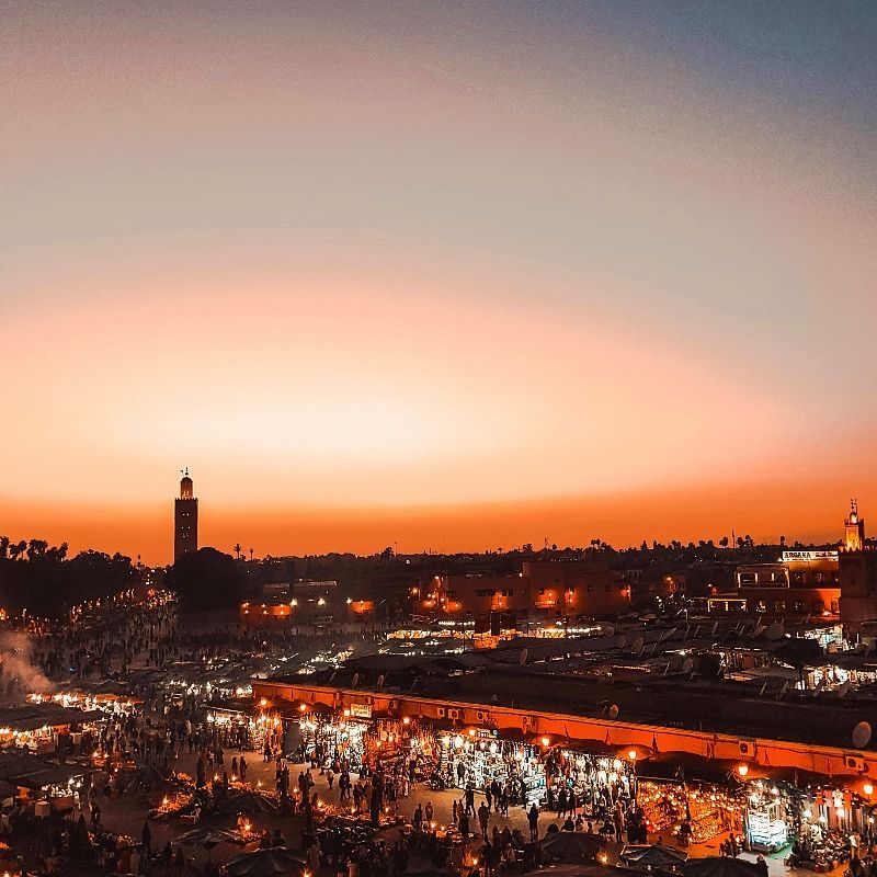 A soft pink and orange sunset glows over the historic Marrakech Medina in Morocco, captured in this atmospheric travel photograph. Warm evening light bathes the city’s rooftops, minarets, and ancient walls, highlighting the rich textures and timeless architecture of this UNESCO-listed old town. As the sun sets, the Medina comes alive with the sounds of daily life, prayer calls, and bustling souks, offering an authentic glimpse into Moroccan culture. Ideal for culture lovers and photographers, this sunset scene showcases Marrakech’s unique blend of history, color, and atmosphere. Inspiration Africa specializes in bespoke, tailor-made journeys to Morocco and across Africa, crafting immersive travel experiences that celebrate iconic cities, cultural heritage, and unforgettable moments.