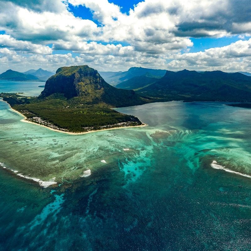 This spectacular aerial image captures Le Morne Brabant in Mauritius, rising dramatically from the coastline and surrounded by turquoise-clear waters, visible coral reefs, and sandy seabeds shimmering beneath the surface. A UNESCO World Heritage Site, Le Morne is not only a natural wonder but also a place of deep cultural significance. The view from above reveals the island’s breathtaking beauty and unique marine landscapes. Inspiration Africa offers tailor-made travel to Mauritius, including scenic flights, beach stays, and cultural experiences. Discover the island’s iconic coastlines and hidden treasures with expertly crafted journeys from Inspiration Africa.