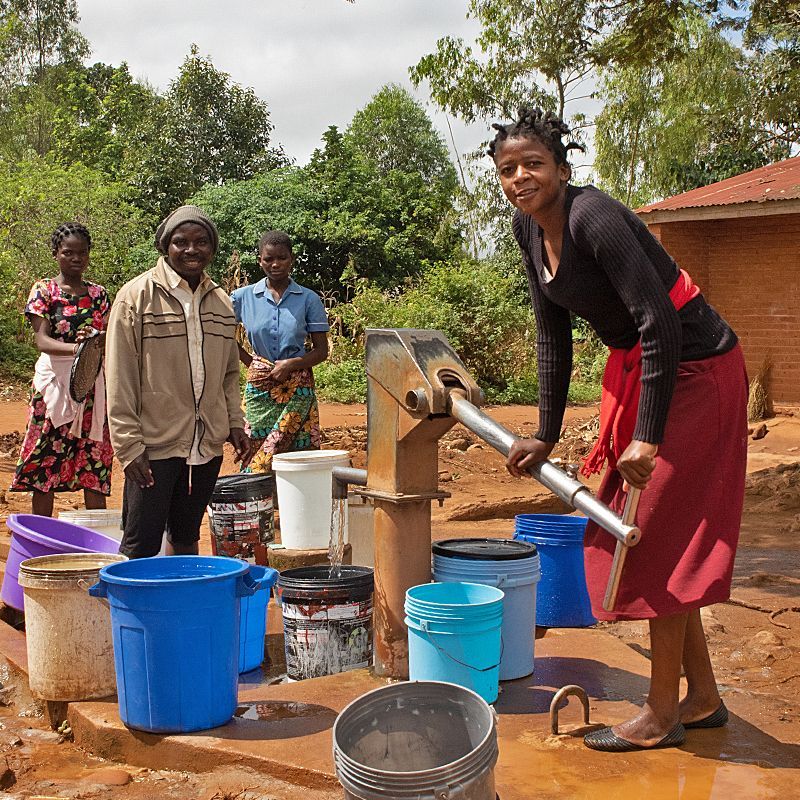 Children awaiting their turn to fill their buckets at a water pump.