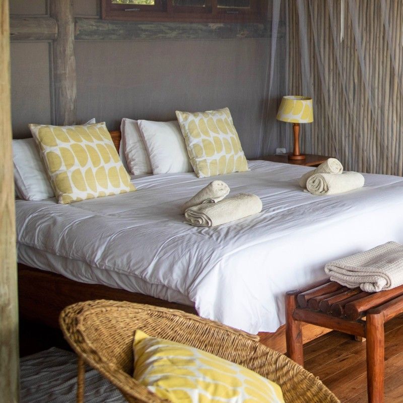 One of the bedrooms at Travessia Beach Lodge in Mozambique is captured in this welcoming travel photograph, showcasing a light-filled, coastal-inspired space designed for rest and relaxation. Soft neutral tones, natural wooden furnishings, and crisp linens create a calm and comfortable atmosphere, while thoughtful details reflect the lodge’s understated beachside style. Large windows or open doors invite in fresh ocean air and natural light, often revealing views of the surrounding greenery or nearby shoreline. The scene conveys simplicity, comfort, and a strong connection to the coastal environment, highlighting Travessia Beach Lodge as a relaxed yet refined retreat on Mozambique’s unspoiled coastline. Inspiration Africa specializes in bespoke, tailor-made journeys to Mozambique and across Africa, crafting unforgettable travel experiences in extraordinary destinations.
