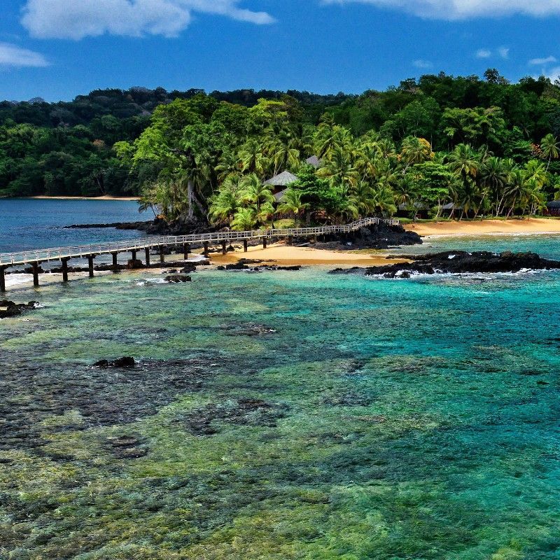 BomBom Island in São Tomé and Príncipe is captured from the ocean in this breathtaking travel photograph, showcasing the island’s pristine beaches, lush tropical vegetation, and sparkling turquoise waters. The coastline curves gently, dotted with thatched lodges and shaded areas, blending seamlessly into the natural surroundings. The vibrant contrast between the green forest, white sandy shores, and deep blue ocean emphasizes the island’s unspoiled beauty and sense of seclusion. This scene conveys the magic of a remote island escape, highlighting BomBom as a luxurious and tranquil retreat in São Tomé and Príncipe. Inspiration Africa specializes in bespoke, tailor-made journeys to São Tomé and Príncipe and across Africa, crafting unforgettable travel experiences in extraordinary destinations.
