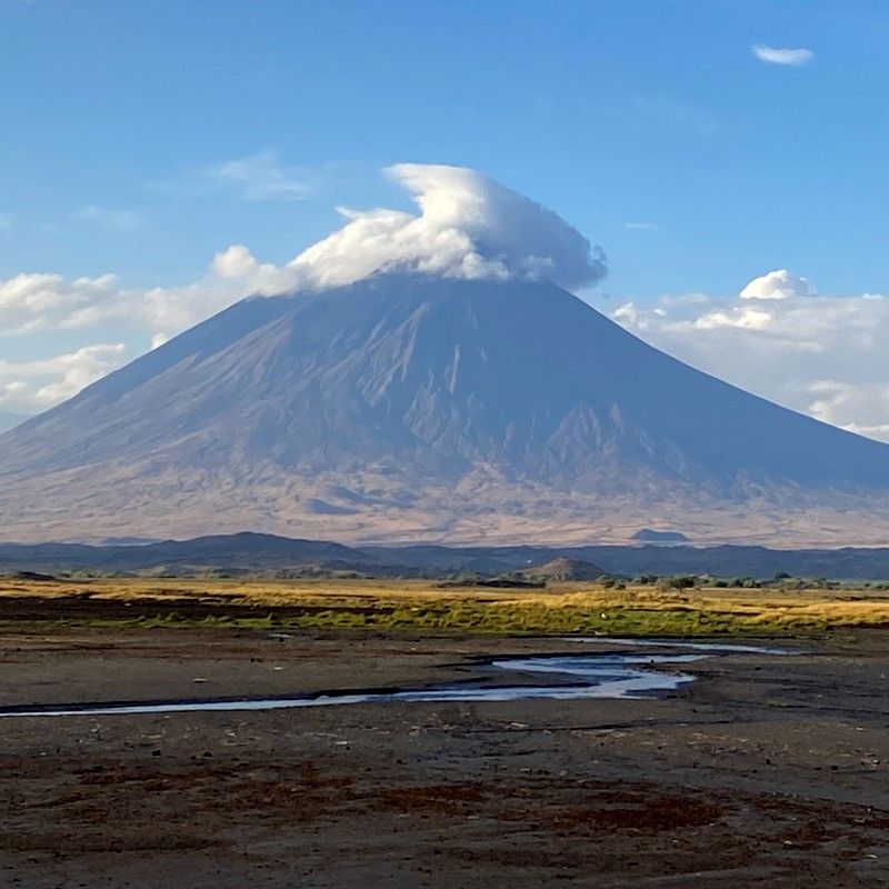 Adventurers hike near Ol Doinyo Lengai, Tanzania’s sacred “Mountain of God,” captured in this dramatic travel photograph. This active volcano, revered by the Maasai and famous for its rare carbonatite lava, rises sharply against the East African landscape, offering one of the region’s most unique trekking experiences. Hikers navigate volcanic slopes and rugged terrain while enjoying sweeping views of the surrounding plains and Rift Valley escarpments. Ideal for adventure seekers, photographers, and geology enthusiasts, trekking Ol Doinyo Lengai combines physical challenge, cultural significance, and extraordinary natural beauty. Inspiration Africa specializes in bespoke, tailor-made journeys to Tanzania and across Africa, crafting authentic, immersive adventures in remarkable destinations.
