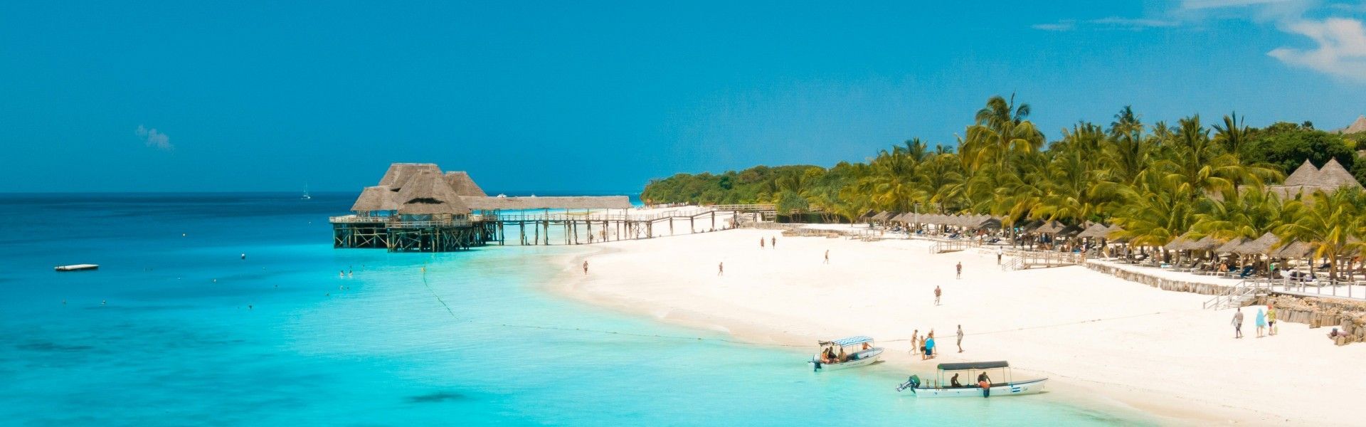 Welcome to paradise! This stunning photo captures the essence of a perfect Zanzibar beach, featuring impossibly clear turquoise water lapping against dazzling white sand. Lush green vegetation and swaying palm trees frame the idyllic scene, promising ultimate relaxation. Inspiration Africa specializes in designing your ultimate, tailor-made trip to Zanzibar and many other incredible destinations across Africa. Book your dream island escape with us today!