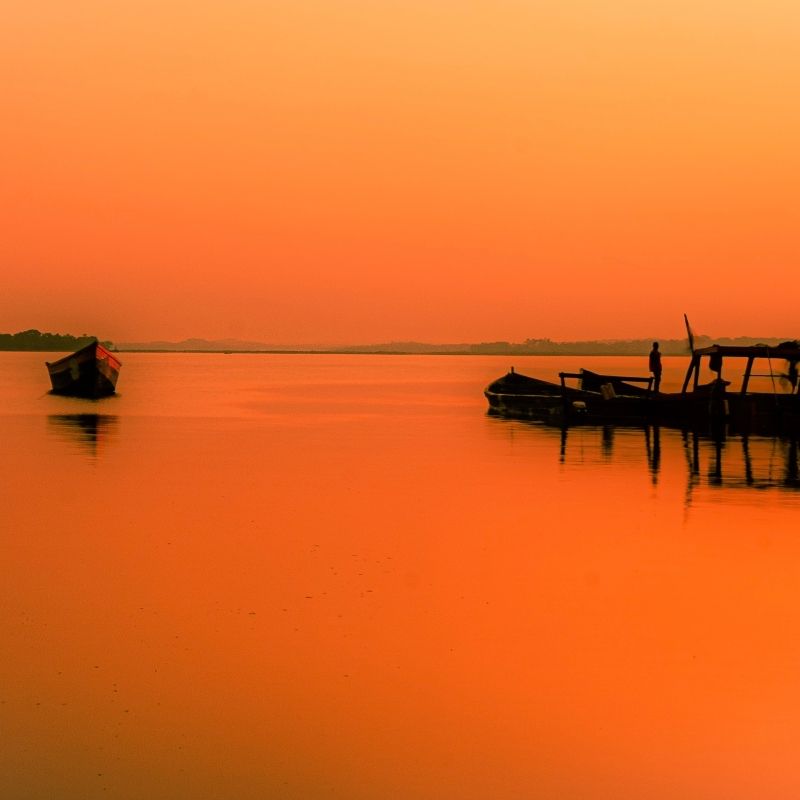Experience Uganda's Lake Victoria at sunset, where the sky transforms into a canvas of vibrant hues, reflecting off the tranquil waters—a serene moment capturing Africa's natural beauty.