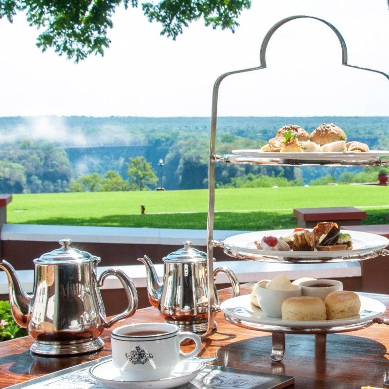 High tea at The Victoria Falls Hotel in Zimbabwe is beautifully captured in this elegant travel photograph, showcasing a refined dining experience set against the hotel’s historic and iconic surroundings. Delicately arranged tiers of pastries, finger sandwiches, and fine china are presented on pristine tables, reflecting a timeless tradition of classic hospitality. The setting conveys an atmosphere of sophistication and leisure, often enjoyed on the hotel’s terrace with views toward the Victoria Falls Bridge and surrounding gardens. This scene highlights the blend of heritage, luxury, and indulgence that defines high tea at The Victoria Falls Hotel. Inspiration Africa specializes in bespoke, tailor-made journeys to Zimbabwe and across Africa, crafting unforgettable travel experiences in extraordinary destinations.
