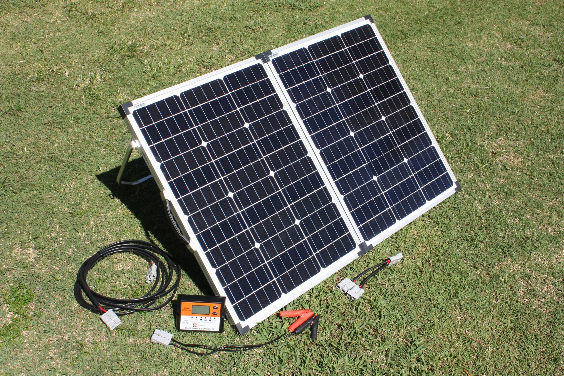 Foldable solar panel on grass with charging cable, controller, and clamps. — Rainbow Beach 4x4 Accessories in Rainbow Beach, QLD