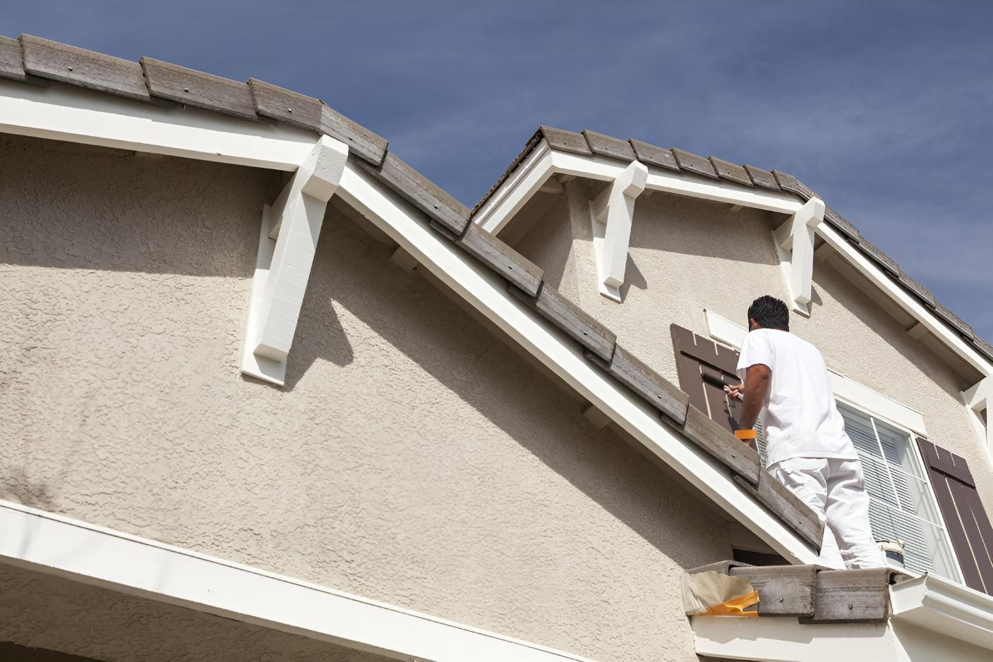 A Man is Painting the Side of a House — Tropical Coats Painting Whitsundays in Airlie Beach, QLD