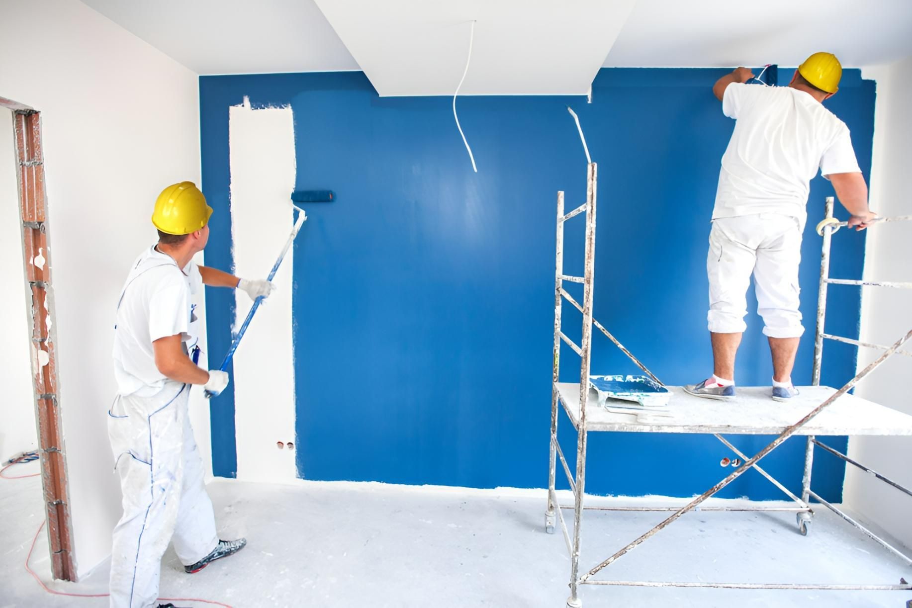 Two Men Are Painting a Blue Wall in a Room — Tropical Coats Painting Whitsundays in Cannonvale, QLD