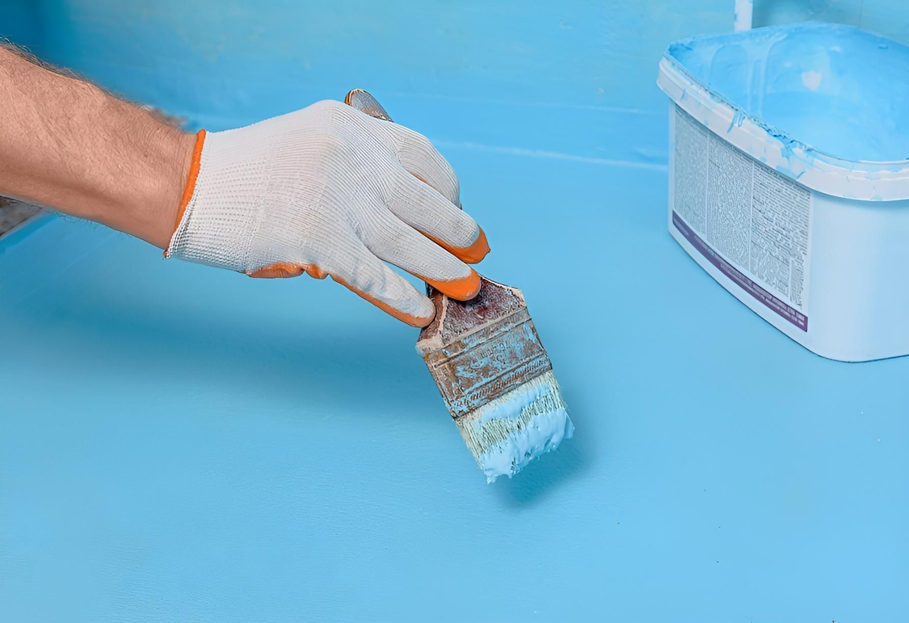 A Person is Painting a Blue Surface With a Brush — Tropical Coats Painting Whitsundays in Cannonvale, QLD