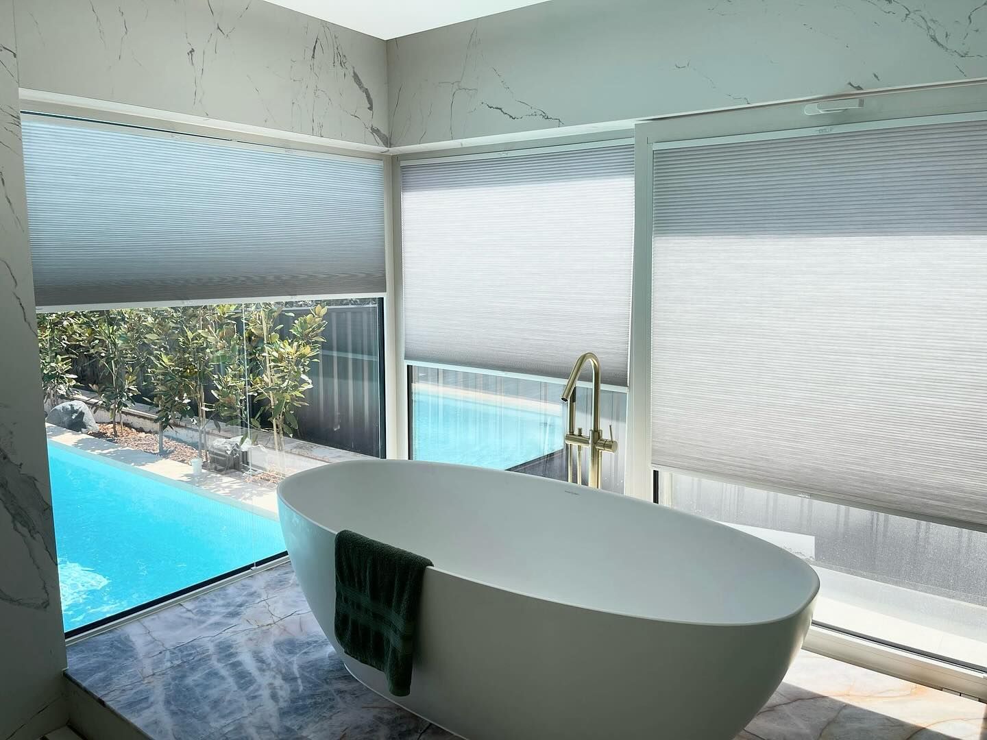 A bathroom with a bathtub and a swimming pool in the background — Elite Window Furnishings In Fyshwick, ACT