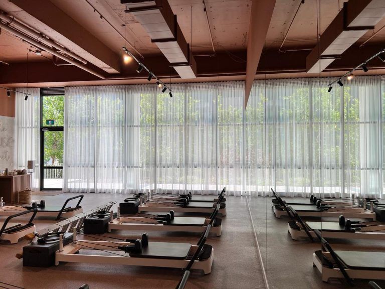 A Row of Pilates Machines Are Lined Up in a Large Room — Elite Window Furnishings In Fyshwick, ACT