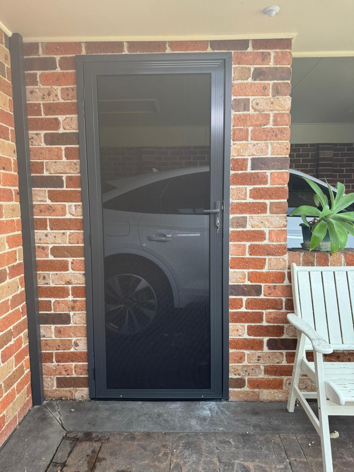 A white car is parked in a garage next to a brick wall — Elite Window Furnishings In Fyshwick, ACT