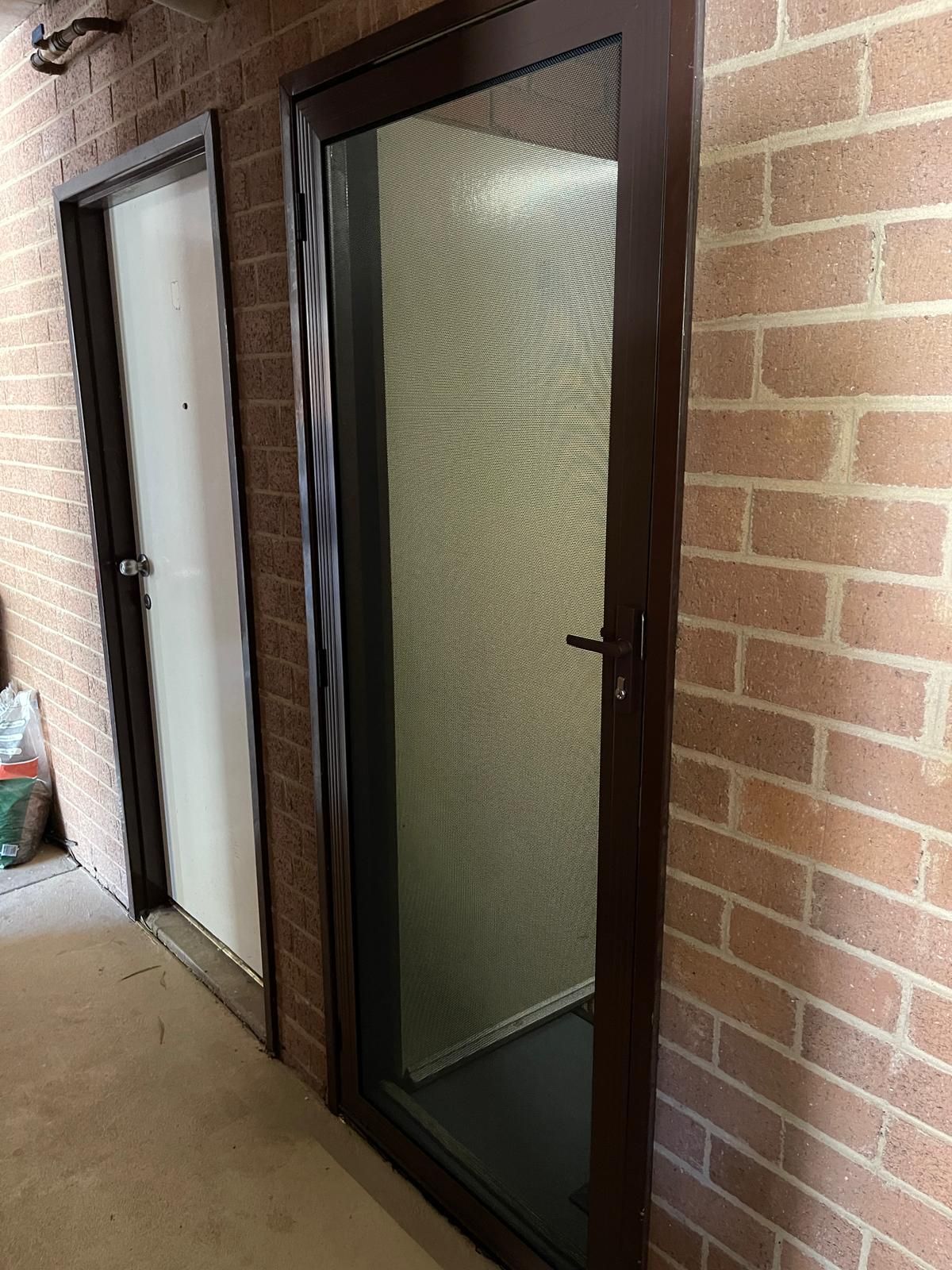 A hallway with two doors and a brick wall — Elite Window Furnishings In Fyshwick, ACT