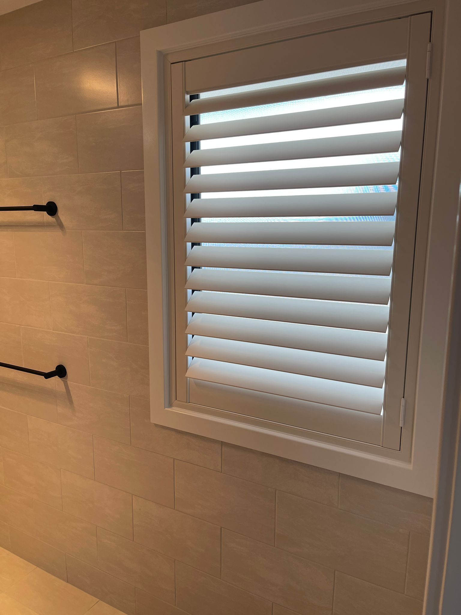 A bathroom with a window with shutters on it — Elite Window Furnishings In Fyshwick, ACT