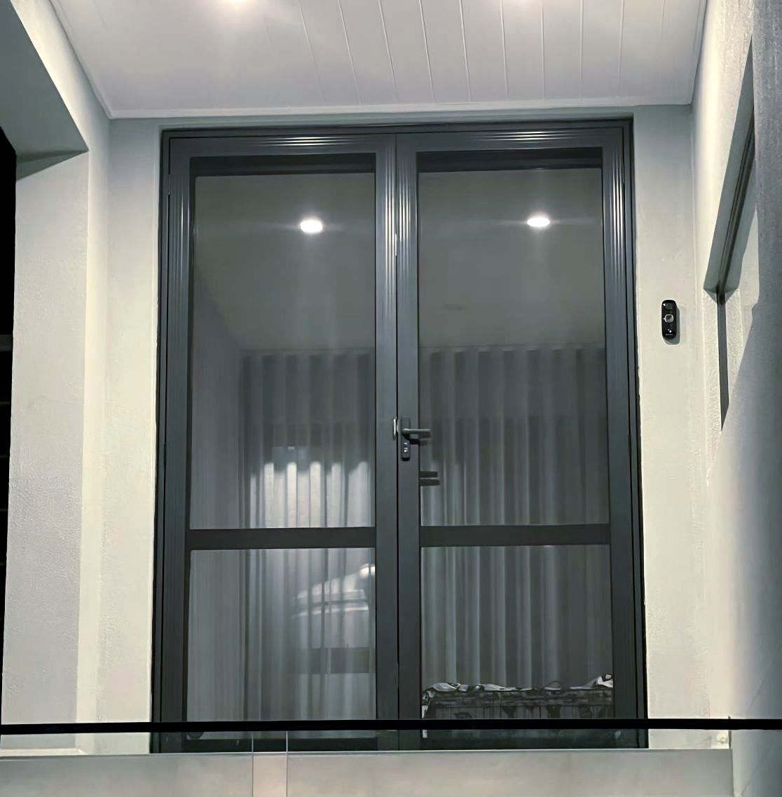 A balcony with a sliding glass door and a glass railing — Elite Window Furnishings In Fyshwick, ACT