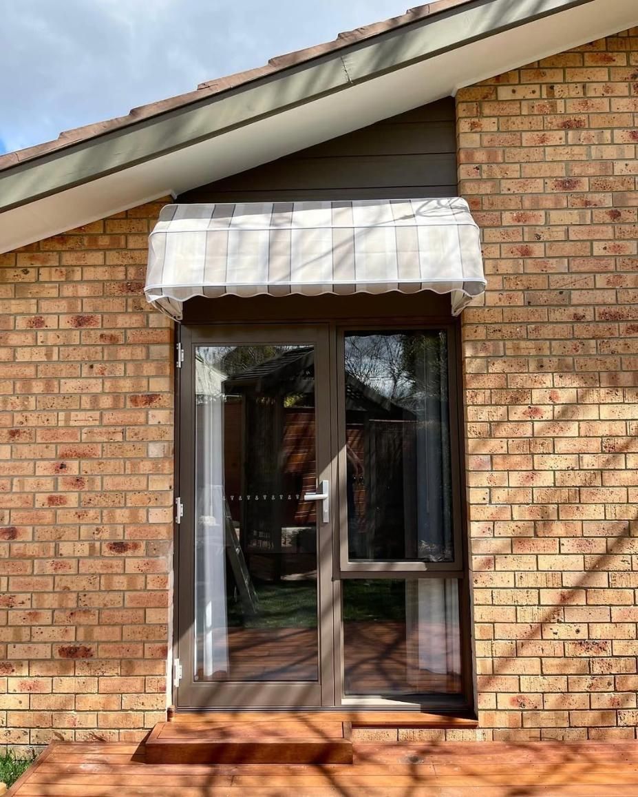 A brick house with a window and a canopy over it — Elite Window Furnishings In Fyshwick, ACT