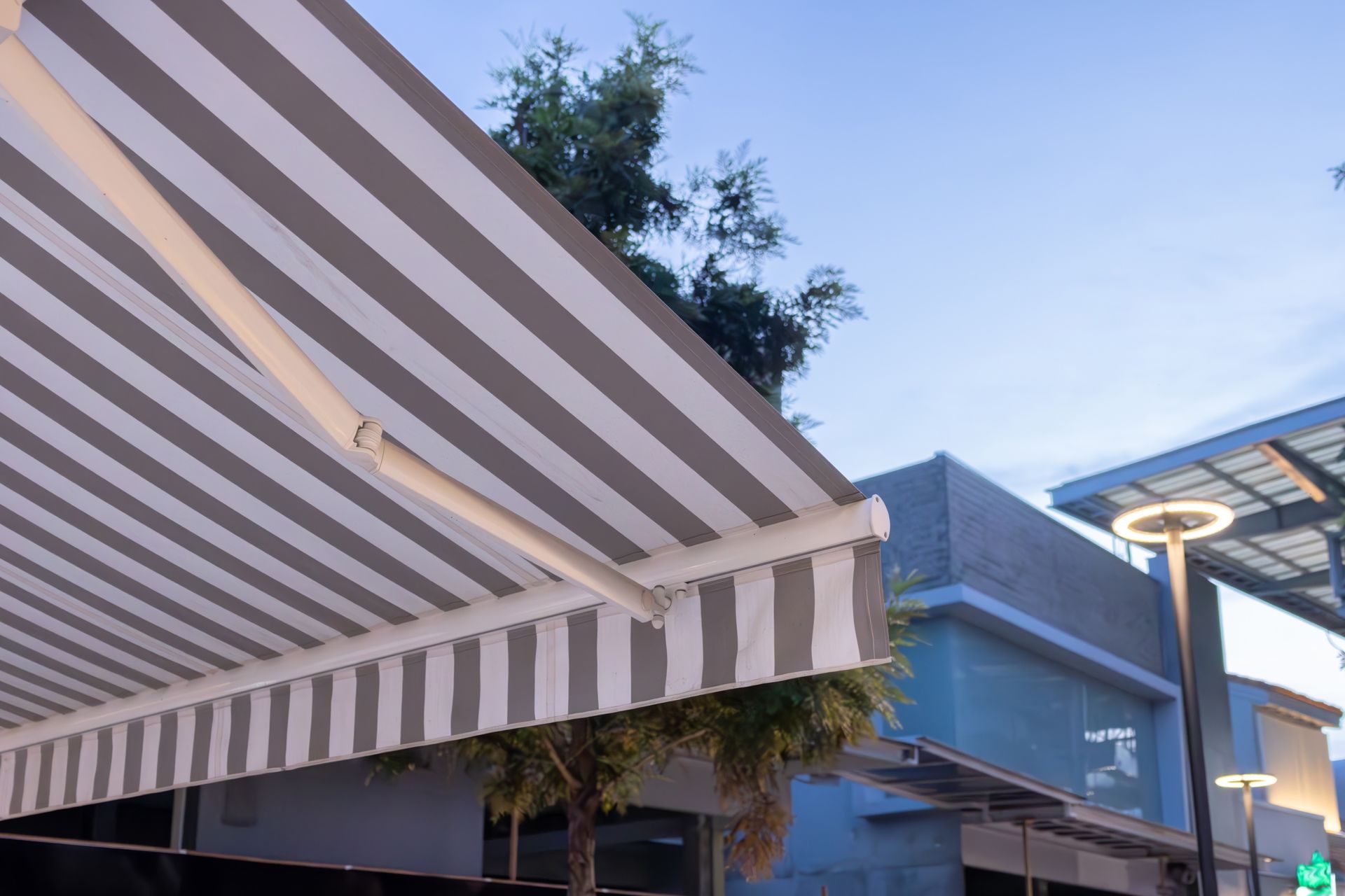A Striped Awning is Sitting on Top of a Building in a City — Elite Window Furnishings In Fyshwick, ACT