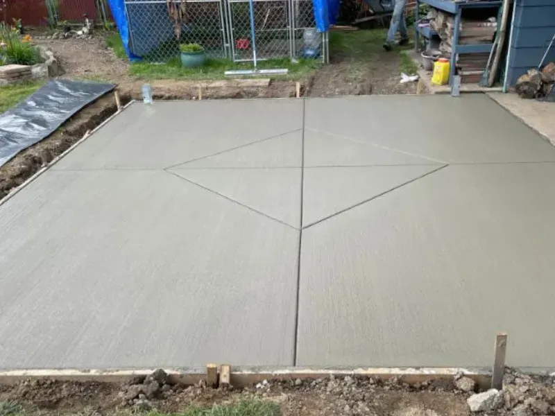 Freshly poured concrete patio with diamond-shaped scoring, outdoors.