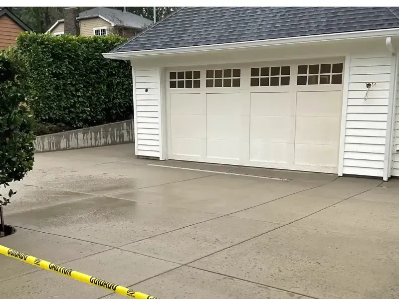 White garage with a concrete driveway, yellow caution tape in foreground.