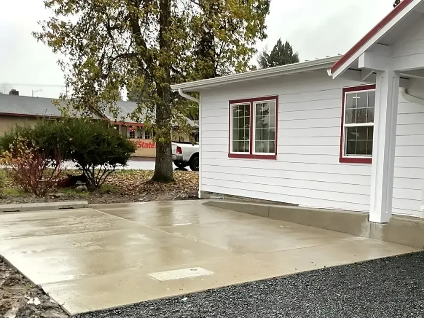 Suburban home with gray paver driveway, green lawn, and a sidewalk.