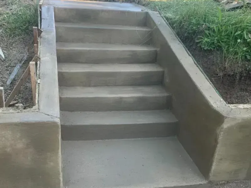 Concrete steps leading up, built into a hillside, with a concrete landing.