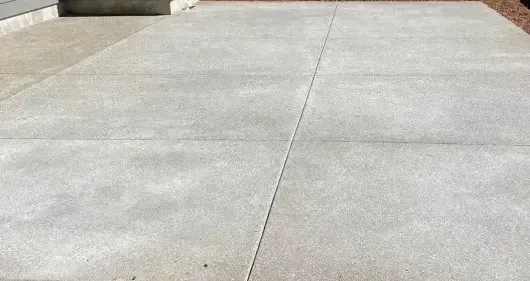 Concrete sidewalk with expansion joints, light gray, sunny outdoor setting.