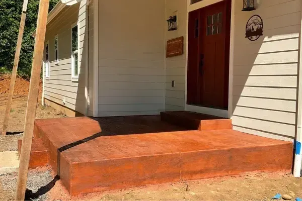 A concrete porch with steps leading to the front door of a house.