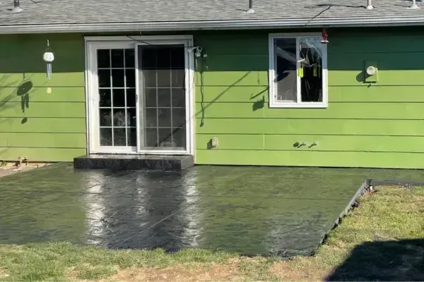 A concrete driveway is being built in a backyard.