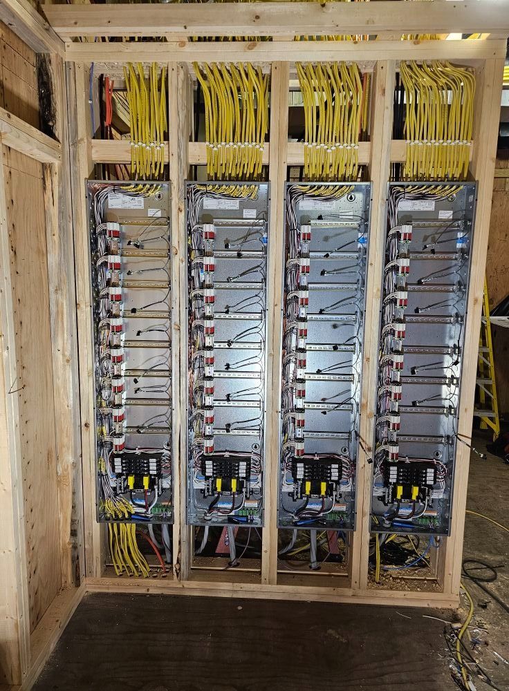Open electrical control cabinets with rows of wiring and modules in an unfinished room