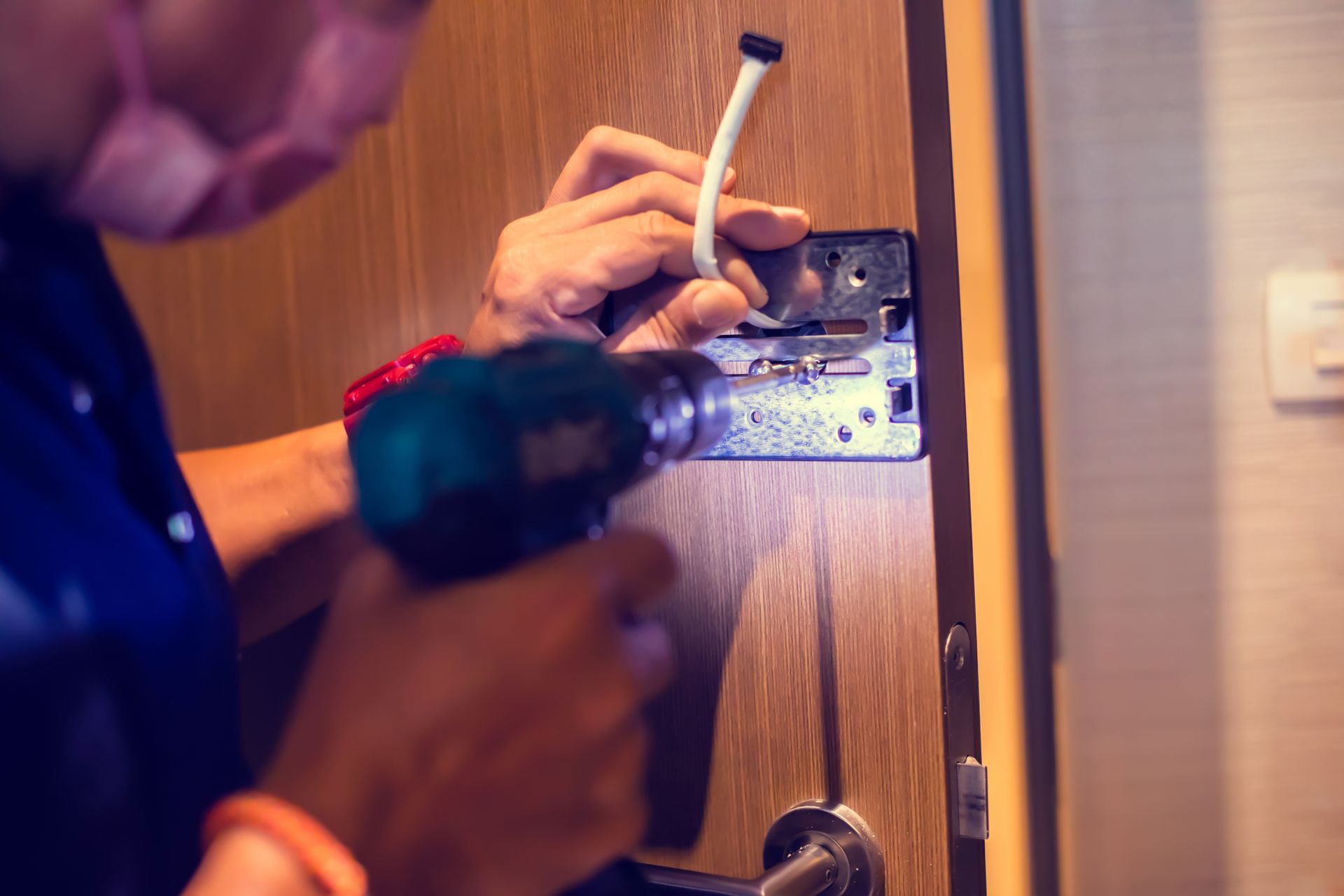 Person using a drill to install a door lock on a wooden door