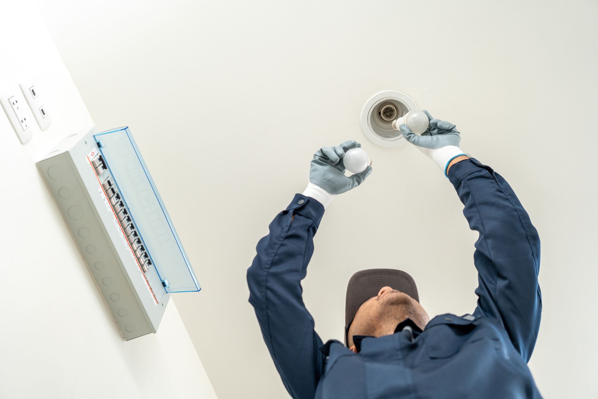 Worker using a drill overhead to install a ceiling light fixture