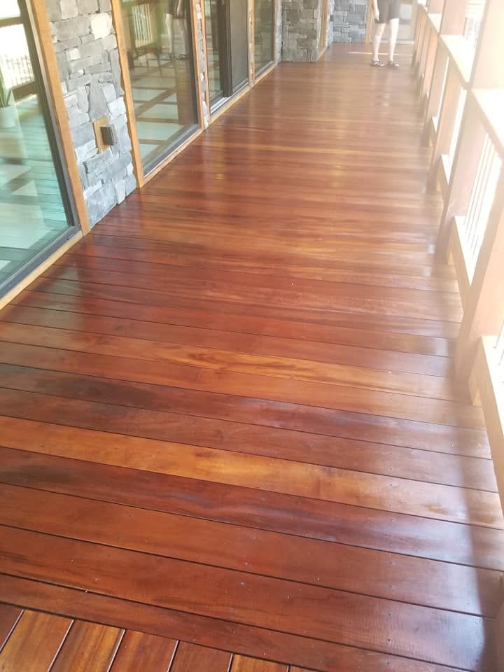 A long wooden walkway leading to a building with a lot of windows.