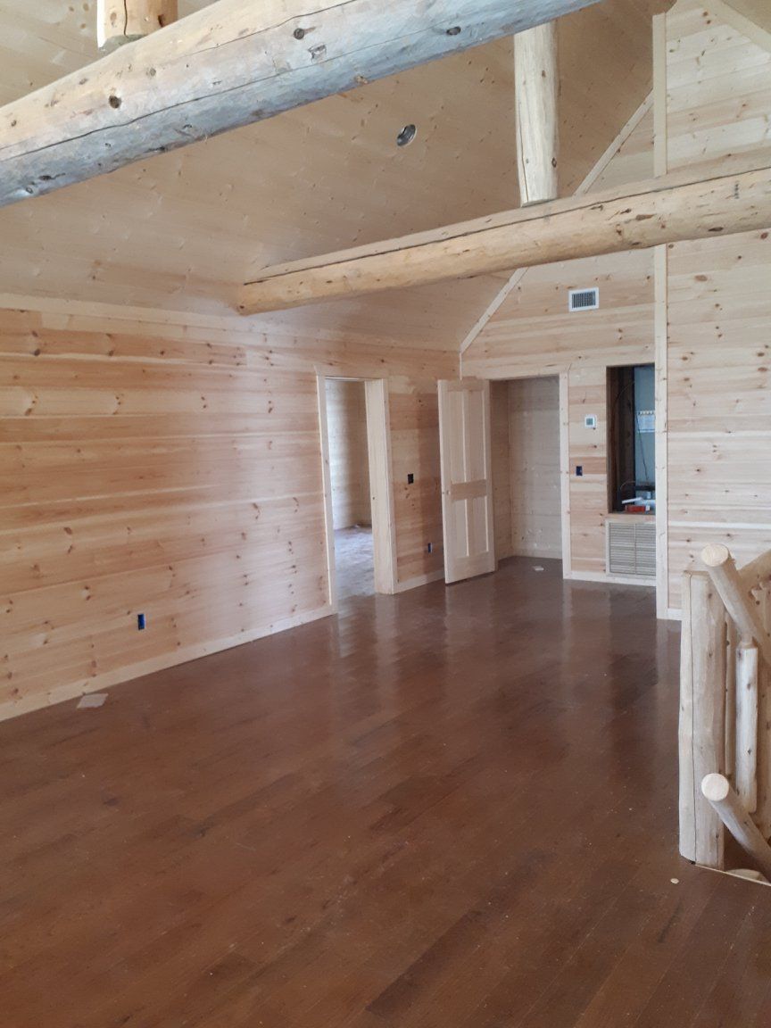 An empty room with wooden walls and floors in a log cabin.