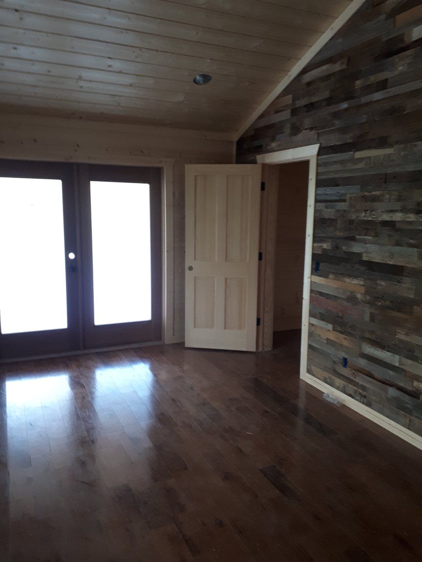 An empty room with hardwood floors and a wooden wall