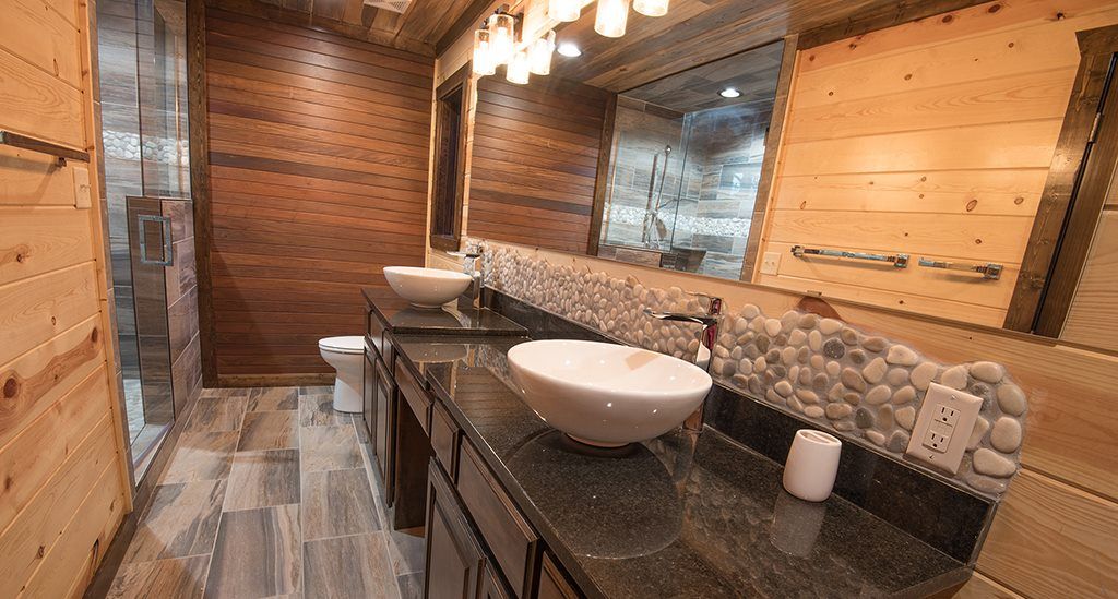 A bathroom with two sinks , a toilet and a mirror.