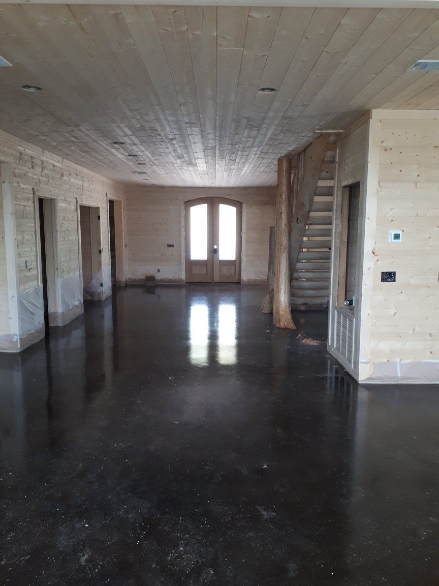 A large empty room with a staircase and a wooden ceiling