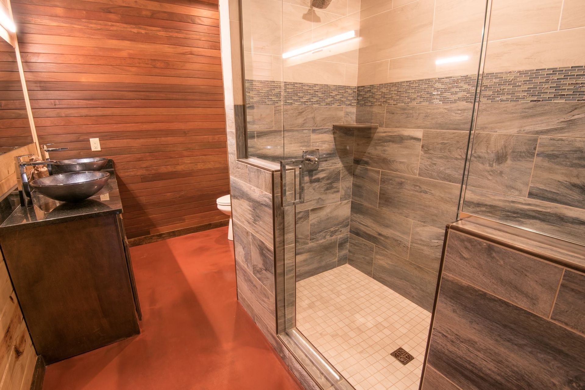 A bathroom with a walk in shower , sink and toilet.