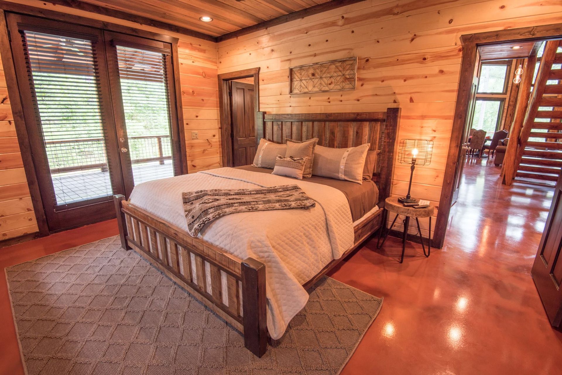 A bedroom in a log cabin with a king size bed and lots of windows.