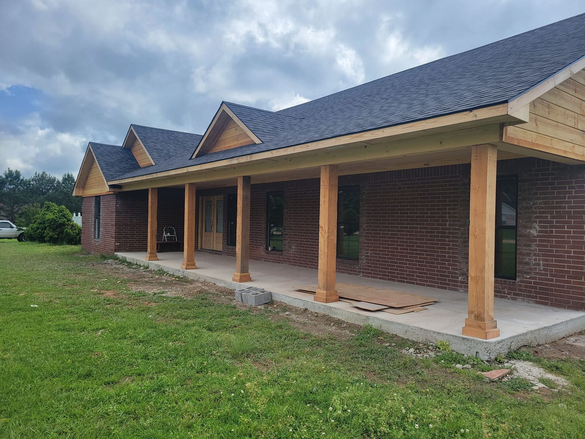A brick house with a porch and a car parked in front of it.