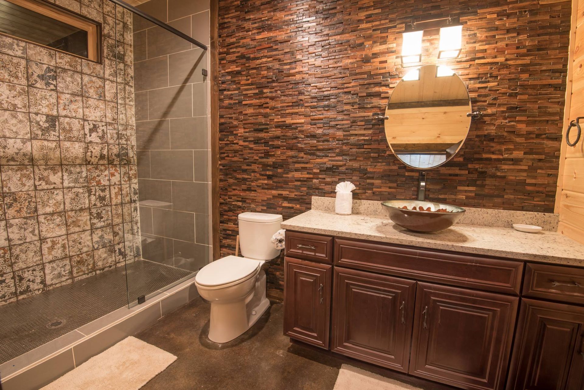 A bathroom with a toilet , sink , mirror and walk in shower.