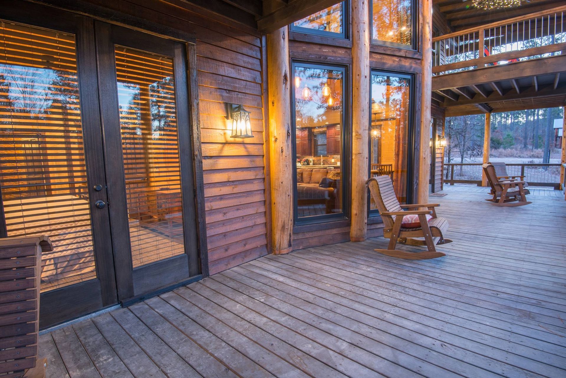 There are rocking chairs on the deck of a log cabin.