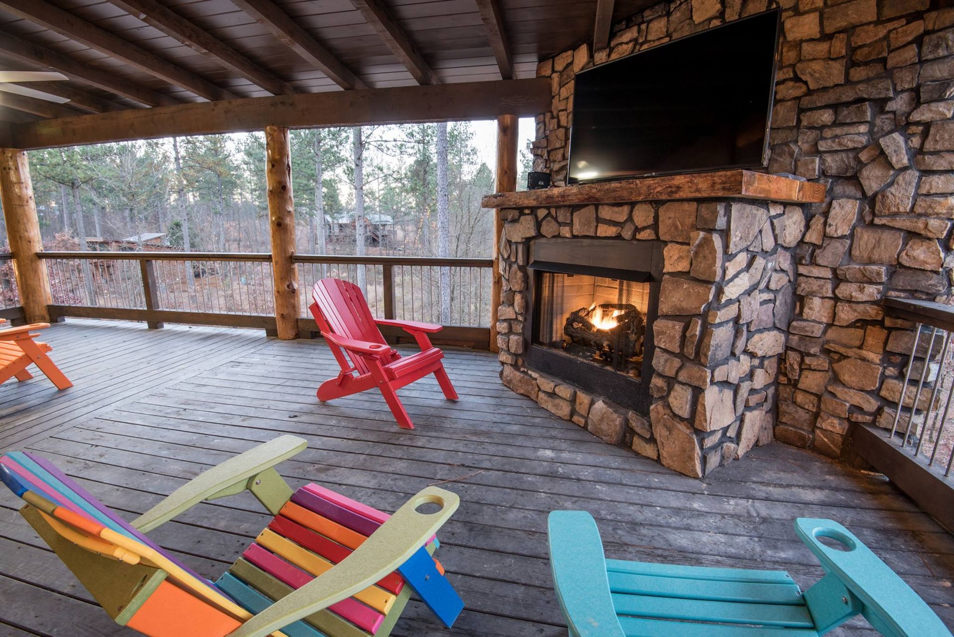 A deck with chairs and a fireplace with a flat screen tv.