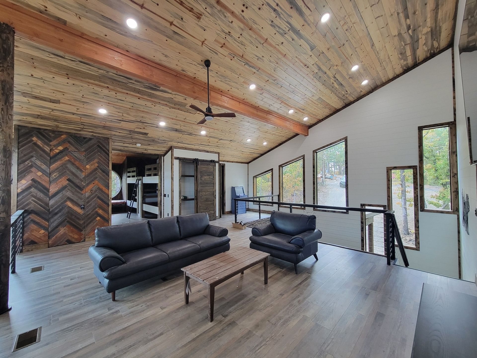 A living room with a couch , chair , coffee table and ceiling fan.