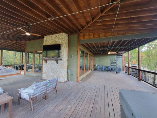 A large wooden deck with a fireplace and a television on it.