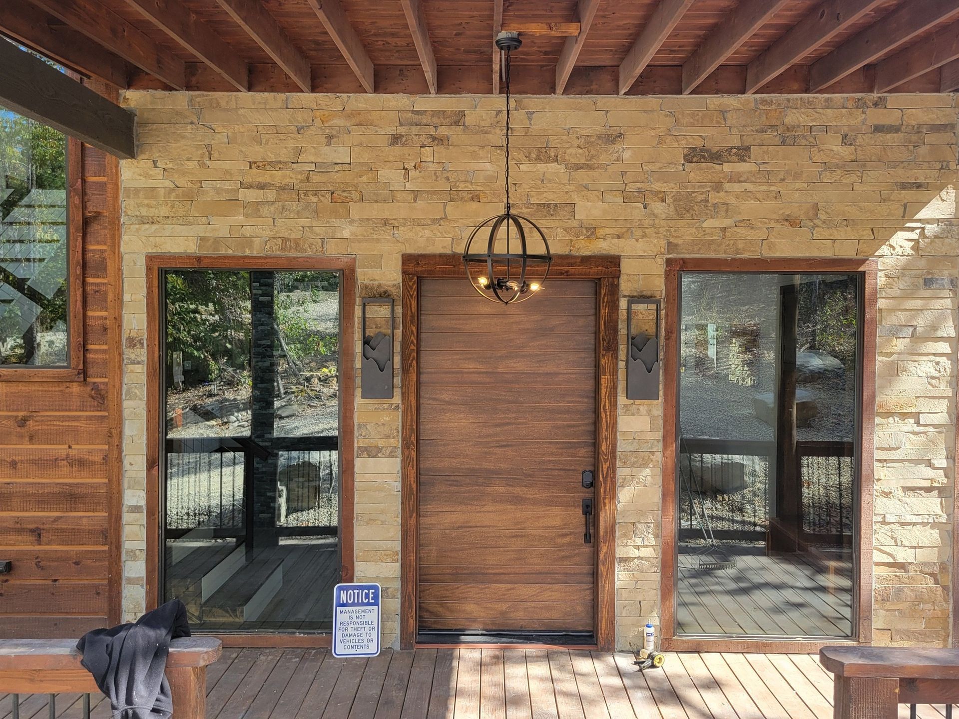 The front door of a wooden house with a chandelier hanging from the ceiling.