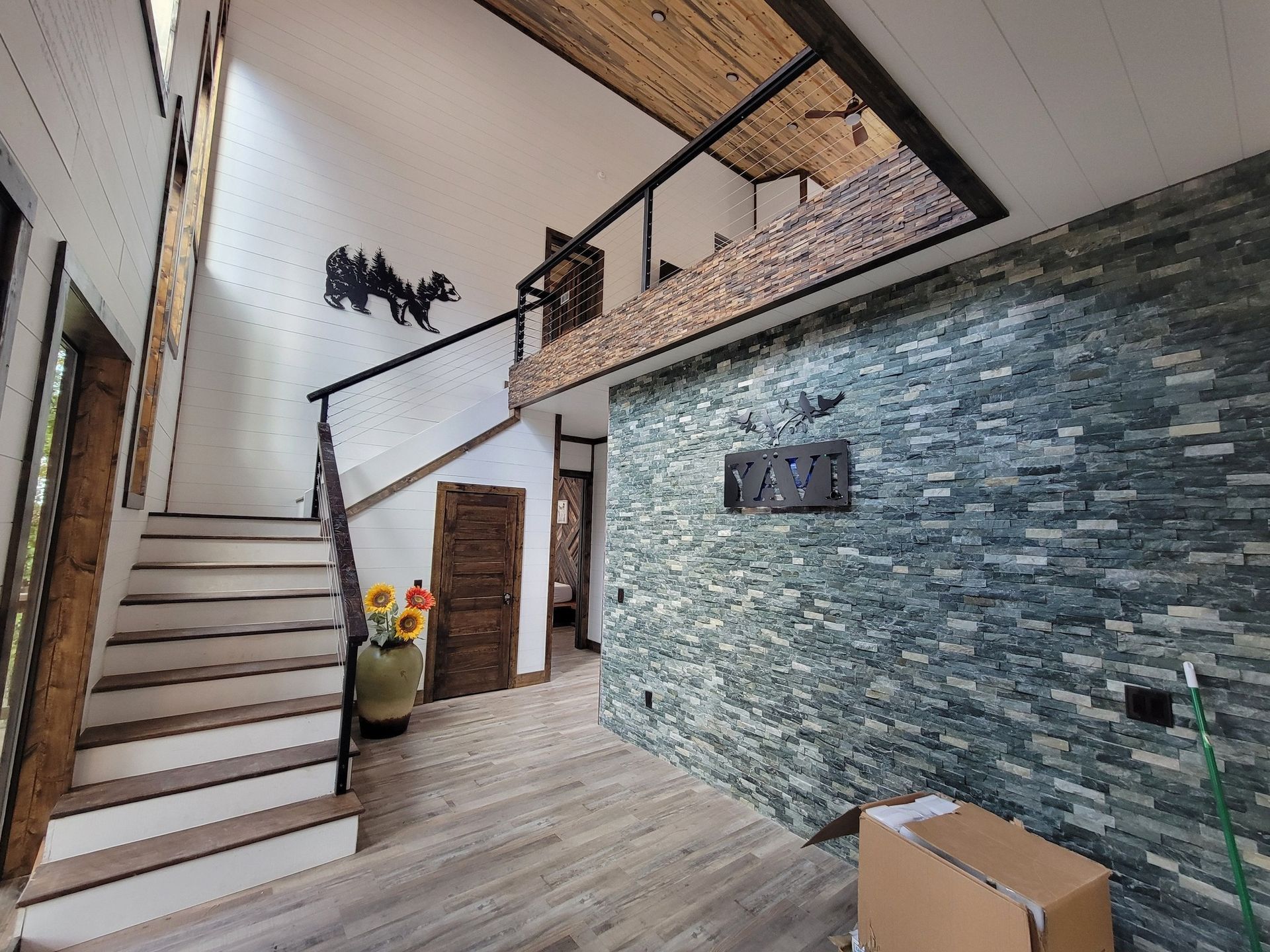 A staircase leading up to a second floor in a house with a stone wall.