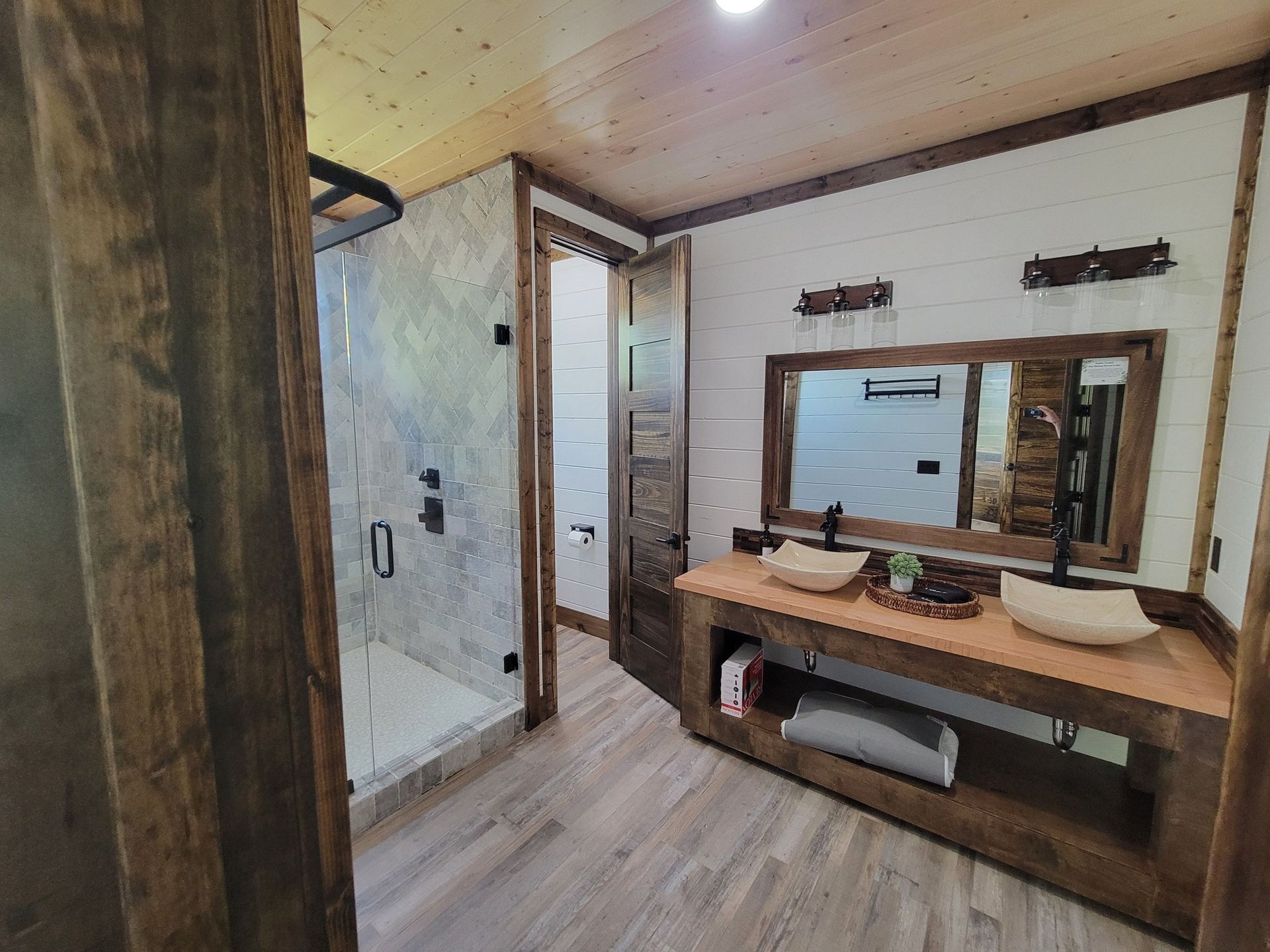 A bathroom with two sinks , a mirror and a walk in shower.